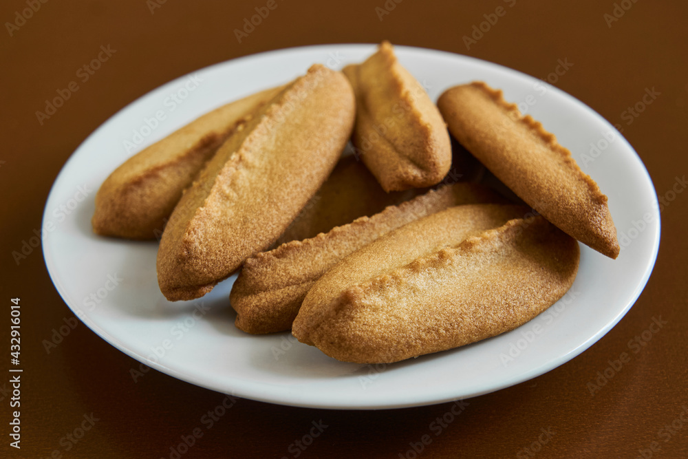 Baked cookies on white plate on brown background. Baked cookies on white plate on brown background.