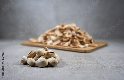 A couple of pistachios and lots of pistachios shells in the background