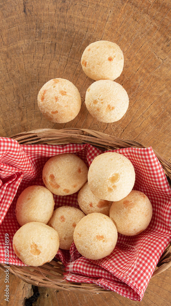 Brazilian cheese bread, basket with checkered cloth with cheese breads on rustic wood, top view. Brazilian cheese bread, basket with checkered cloth with cheese breads on rustic wood, top view.
