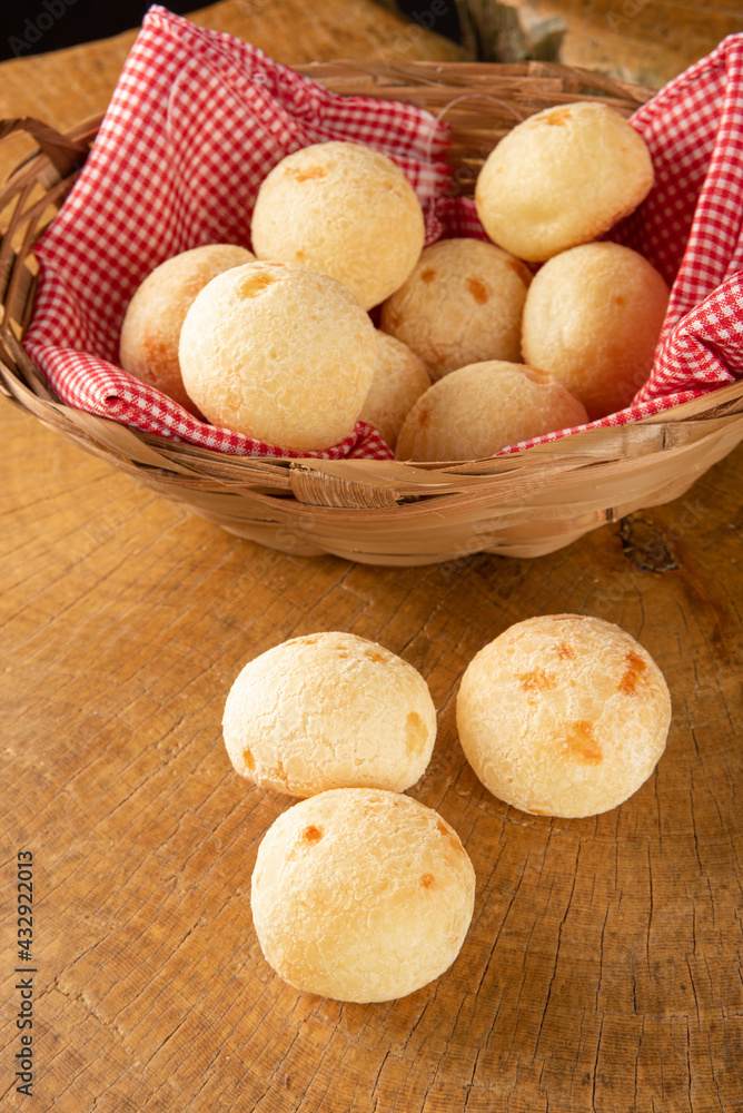 Brazilian cheese bread, basket with checkered cloth with cheese breads on rustic wood, selective focus. Brazilian cheese bread, basket with checkered cloth with cheese breads on rustic wood, selective focus.