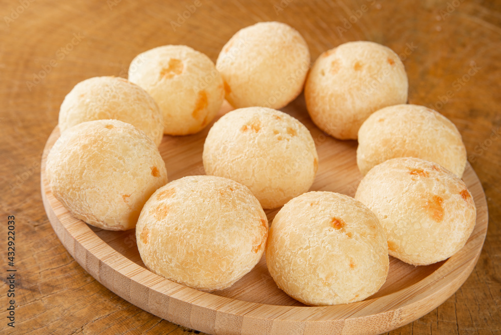 Brazilian Cheese bread, cheese breads arranged on wooden plate, on rustic wood, selective focus. Brazilian Cheese bread, cheese breads arranged on wooden plate, on rustic wood, selective focus.