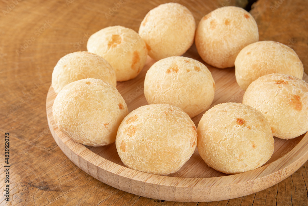 Brazilian Cheese bread, cheese breads arranged on wooden plate, on rustic wood, selective focus. Brazilian Cheese bread, cheese breads arranged on wooden plate, on rustic wood, selective focus.