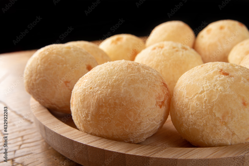 Brazilian Cheese bread, cheese breads arranged on wooden plate, on rustic wood, selective focus. Brazilian Cheese bread, cheese breads arranged on wooden plate, on rustic wood, selective focus.
