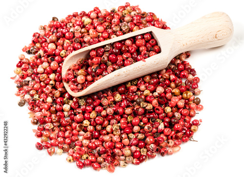 scoop on pile of pink peppercorns on white photo