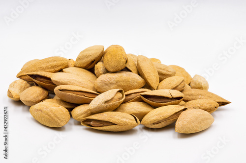 bunch of inshell almonds closeup against white
