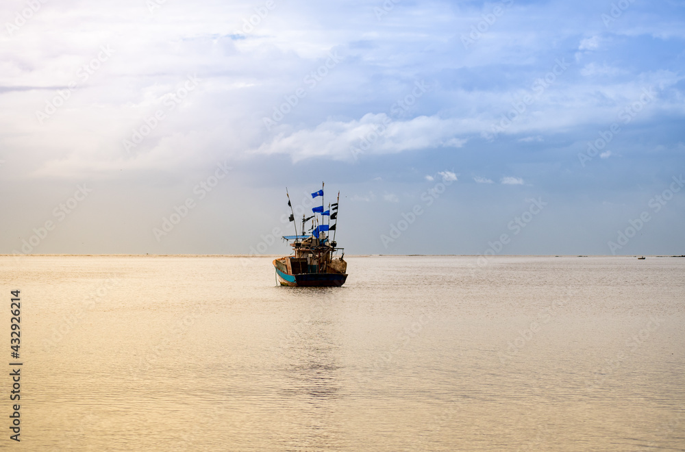 Fototapeta premium Fishing boat in the ocean under the sunlight. Clouds in the sky.