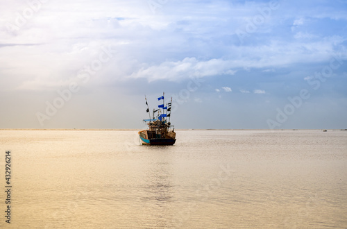 Fishing boat in the ocean under the sunlight. Clouds in the sky.