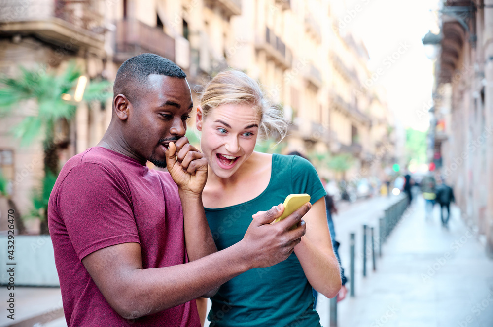 young interracial couple surprised with the mobile screen