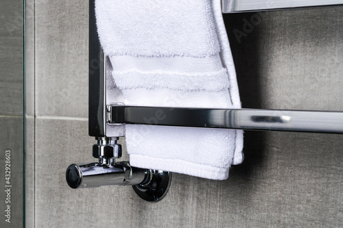 fragment of a chrome steel bathroom towel dryer on the gray anthracite tile wall photo