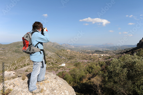 Woman taking a photo of the view from Benimaurell to the Mediterranean coast at Javea on the Costa Blanca, Spain photo