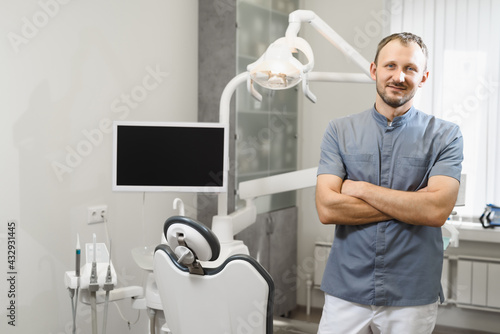 Portrait of a friendly male dentist in his office. Modern dental clinic.