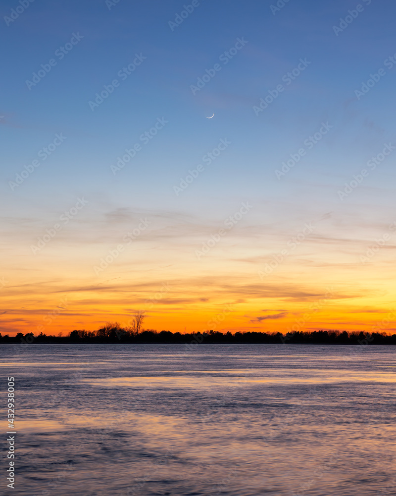 Crescent moon in the sky above the orange glow of dusk over water. Seaside Heights, New Jersey Crescent moon in the sky above the orange glow of dusk over water. Seaside Heights, New Jersey