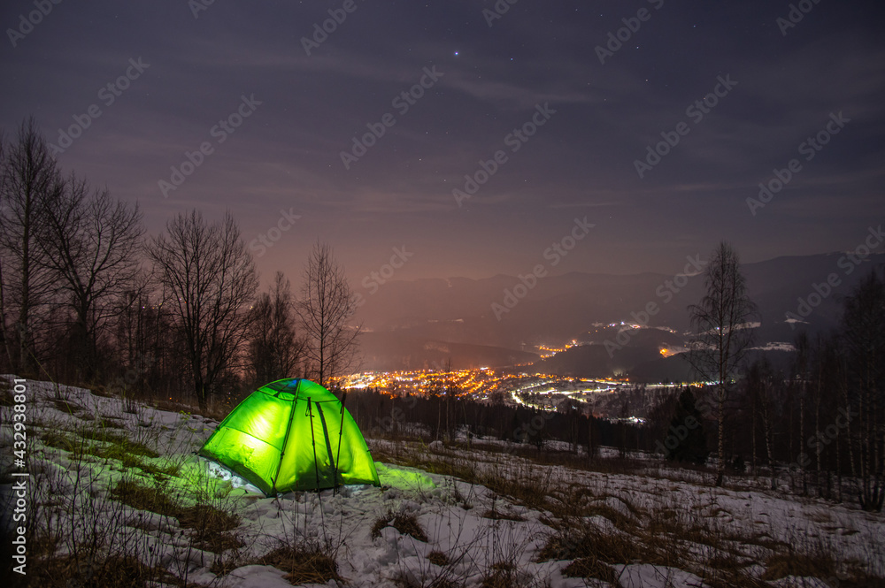 Yellow tent in winter forest at night