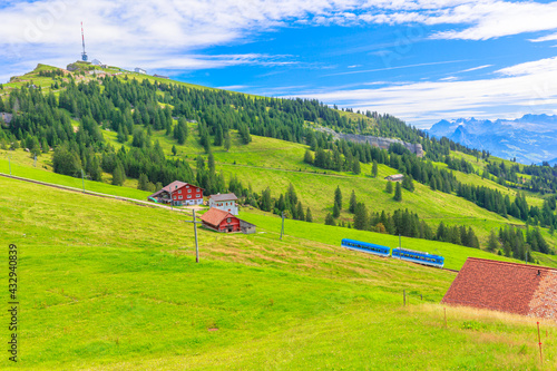 Scenic landscape between Alps, valleys of Rigi Mountain railways and blue cog train. Rigi Kulm summit and telecommunications tower on background. Canton of Schwyz and Lucerne, Central Switzerland. photo