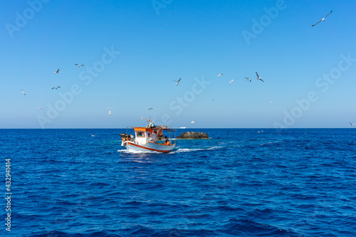 Greek fishing boat and seagulls on mediterranean sea. blue sky and sunny day. traditional fishing concept photo