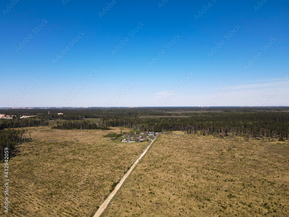 View from the height of the field, forest, village. Panoramic beautiful photo from a drone. Picturesque photo wallpaper, screensaver, cover, background.