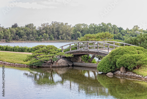 a wooden foot bridge in a park setting with water and trees in the summer