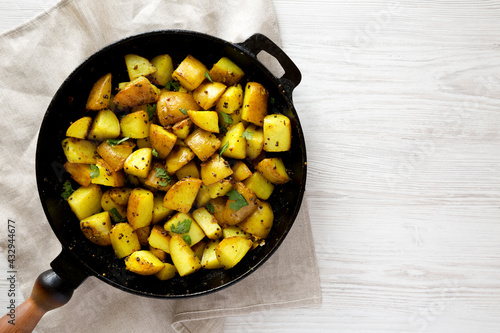 Homemade Roasted Potatoes with Mustard Seeds in a cast-iron pan, top view. Flat lay, overhead, from above. Space for text.