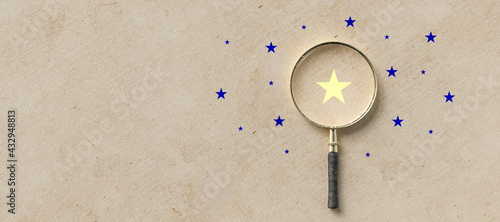 magnifying glass with a yellow star mark as symbol for finding a solution on paper background