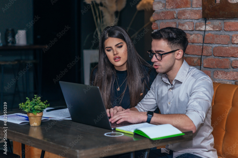 Business meeting inside a cafe with two young colleagues sitting at a table, sharing some new ideas and looking at their laptops Business meeting inside a cafe with two young colleagues sitting at a table, sharing some new ideas and looking at their laptops