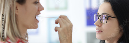 An otolaryngologist examines the patient's throat closeup