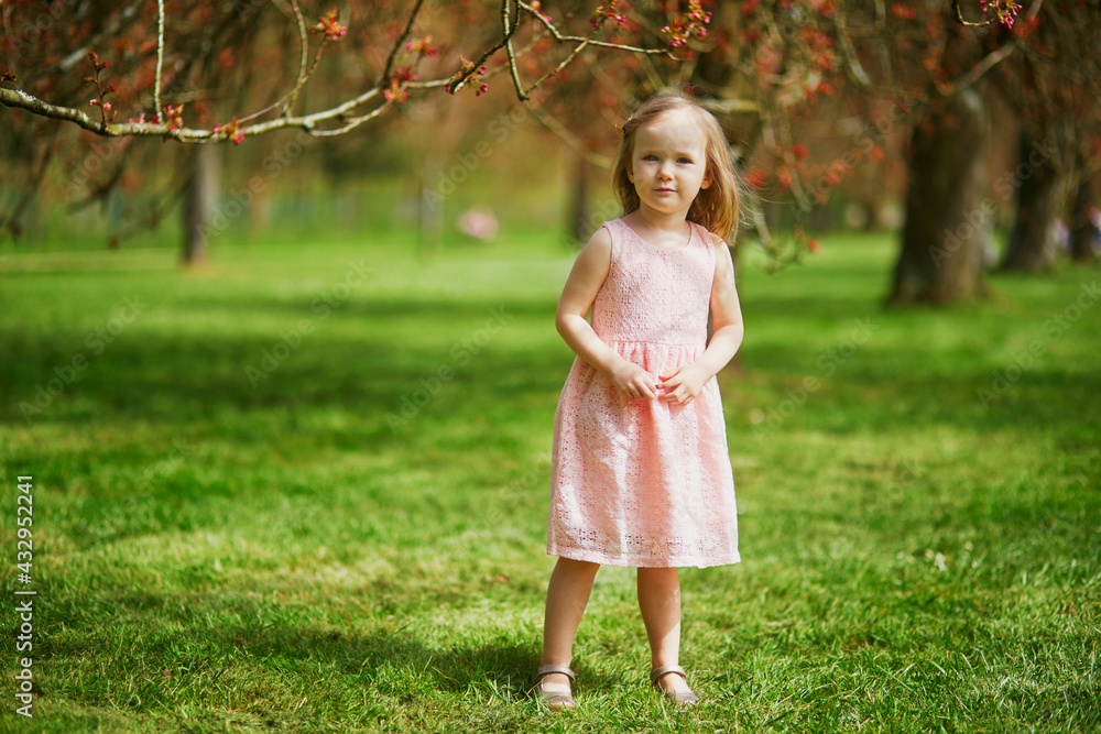 Adorable three year old girl in pink dress enjoying sunny spring day in Park of Sceaux near Paris Adorable three year old girl in pink dress enjoying sunny spring day in Park of Sceaux near Paris