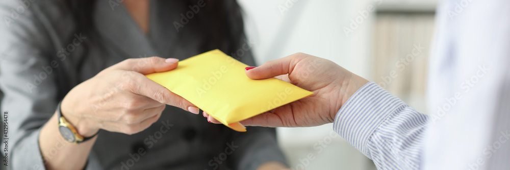 Woman hands over full envelope to her interlocutor Woman hands over full envelope to her interlocutor