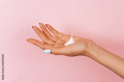a stream of body cream pours onto a woman's hand. Skin moisturizer concept. Copy space