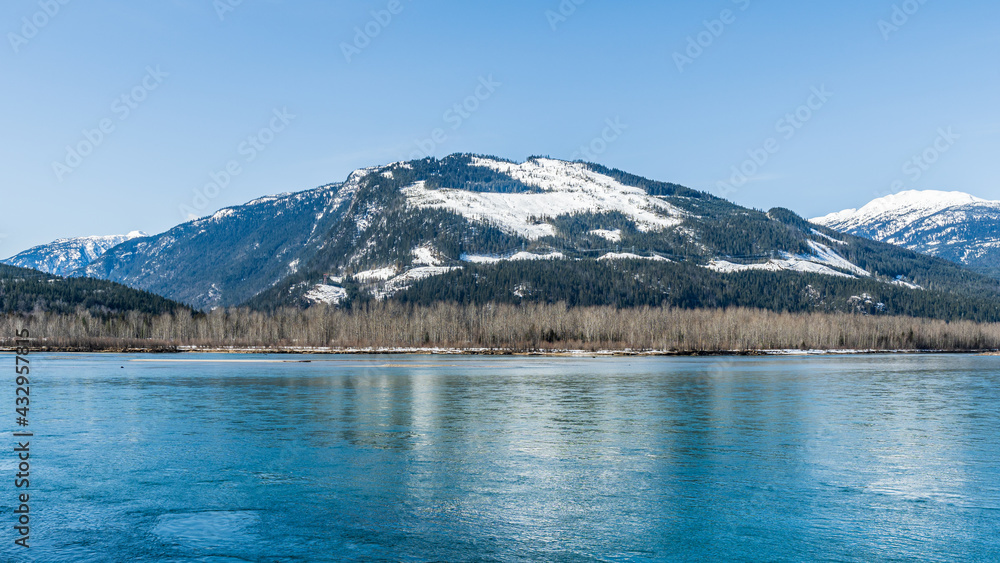 early spring Columbia river with snow on mountains blue sky British Columbia Canada