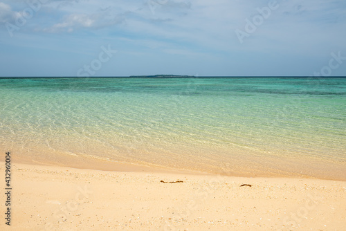 Quiet beach with calm waters and undulations on its surface gently made by the wind, smooth sands and an island in the background composing the cozy and relaxing scene. © Renata Barbarino