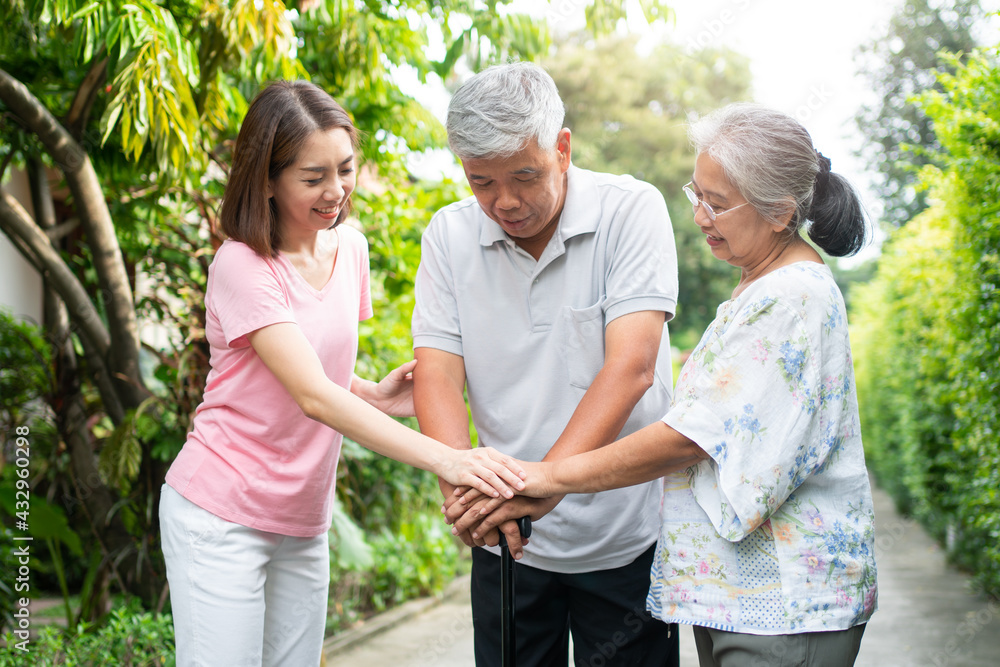 Happy family walking together in the garden. Old elderly using a walking stick to help walk balance. Concept of Love and care of the family And health insurance for family Happy family walking together in the garden. Old elderly using a walking stick to help walk balance. Concept of Love and care of the family And health insurance for family