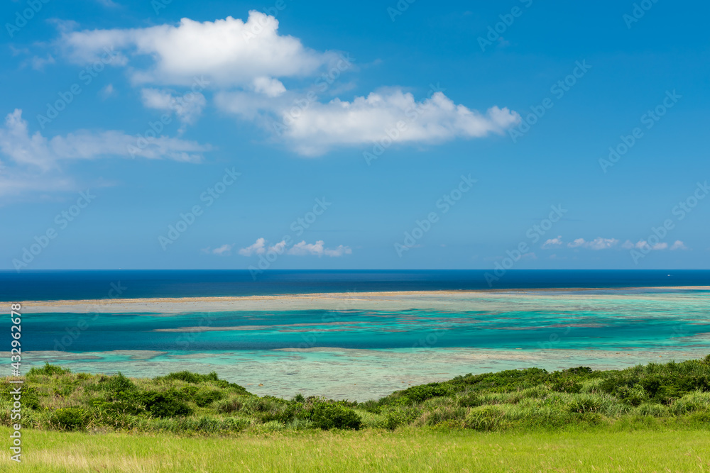 Breathtaking view an unbelievable color ocean, light green till turquoise. Green grass on foreground, blue sky composing the seascape scene.