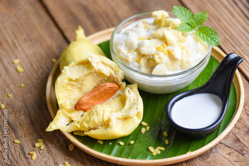 Ripe durian rice cooked with coconut milk, Asian Thai dessert tropical sweet durian peel with yellow bean on wooden plate and fresh mint leaves, Durian sticky rice summer fruit food photo