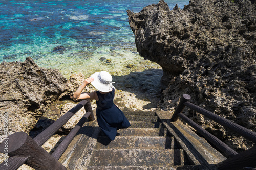 沖縄 浜辺で白い帽子の女性 宮古諸島 伊良部島の海へ続く階段のシンビジ