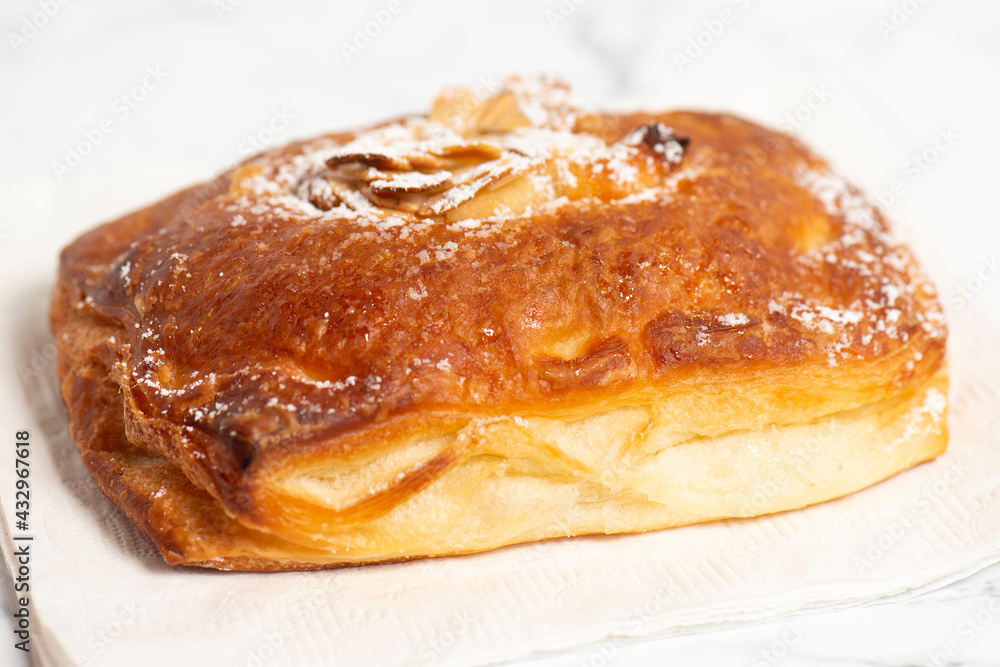Freshly baked croissant filled with almond paste and topped with flakes and icing sugar Freshly baked croissant filled with almond paste and topped with flakes and icing sugar