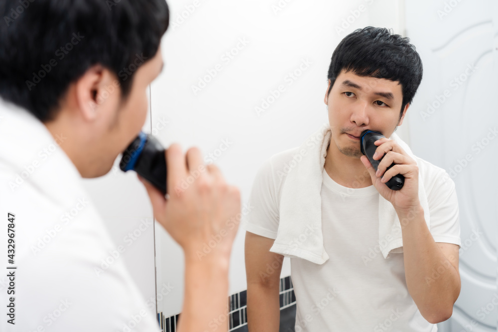 man using electric shave to shaving his face in bathroom mirror man using electric shave to shaving his face in bathroom mirror