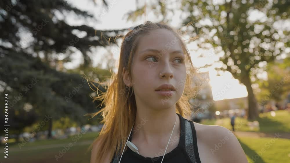 a beautiful red-haired girl with green eyes in the foreground looks straight ahead as the sun of a sunset arrives a beautiful red-haired girl with green eyes in the foreground looks straight ahead as the sun of a sunset arrives