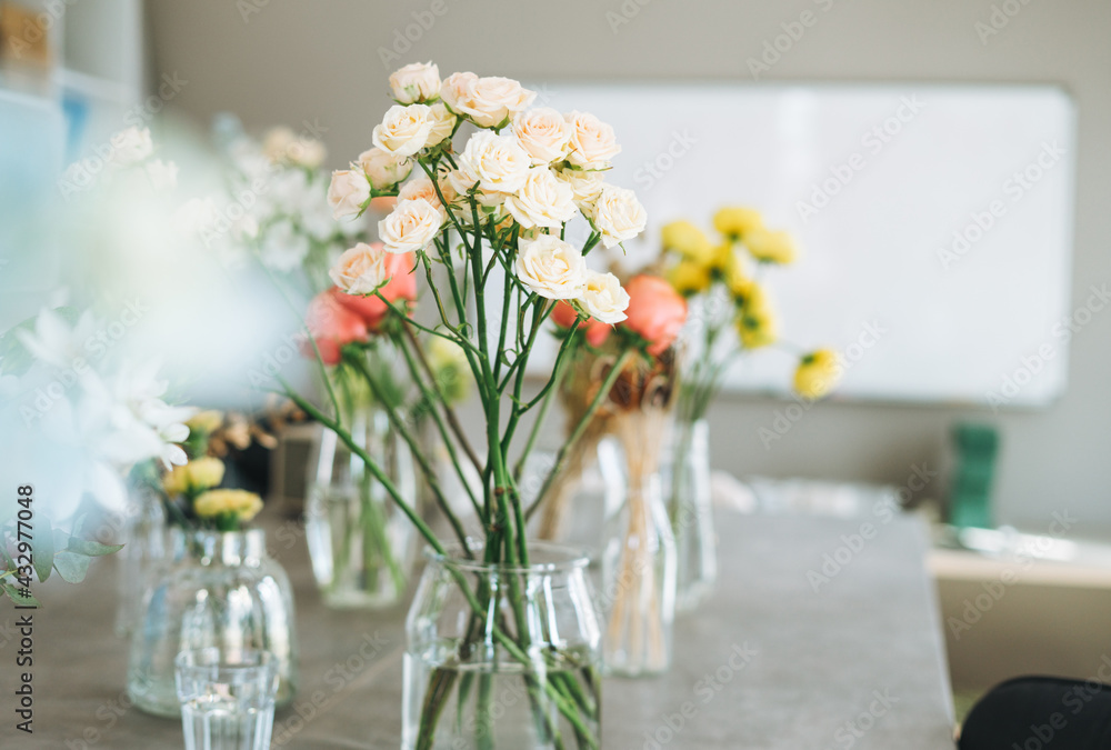 The bouquet of peach roses in glass vase on table. Florist working place The bouquet of peach roses in glass vase on table. Florist working place