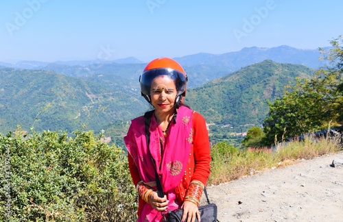 Young Indian woman in helmet standing outside the road in mountains photo