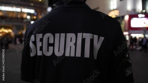 Tracking shot of a security guard walking through a street of a big city at night