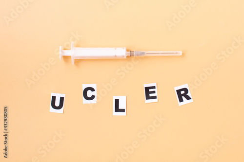 The word ulcer is written on paper and a syringe. Medical concept
