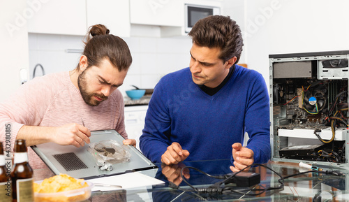 Two men repairing a desktop computer and drink beer. High quality photo