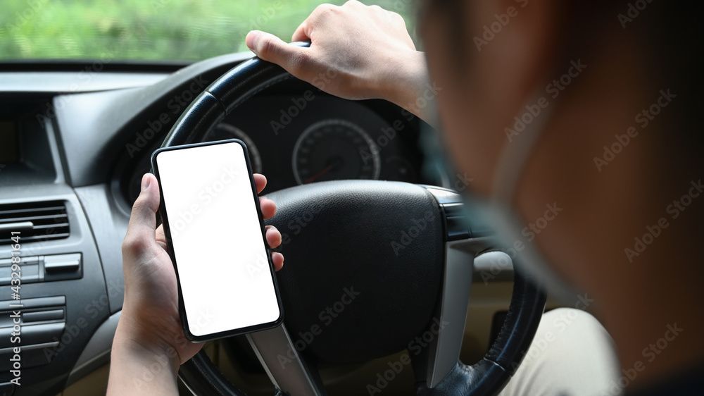 Close up view businessman wearing protective mask and using mobile phone while driving car.