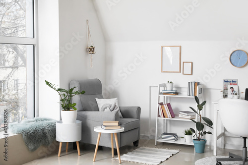 Shelf unit with books and armchair in interior of room © Pixel-Shot