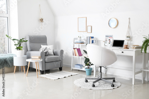 Comfortable workplace and armchair in interior of light room
