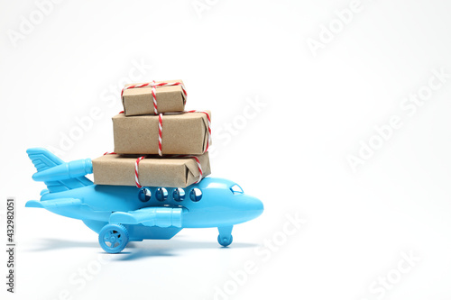 Parcel box on toy airplane in white background with copy space. Air cargo and parcels transportation concept. Fast delivery of goods and products. 