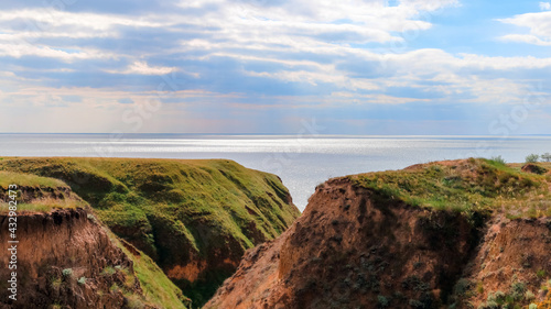 Landscape view clay cape mountains and cliffs near blue sea and skyline. Seascape of coast from green meadows. Clay rock in front of sea. Sea view horizon. Secluded nature tourism. Long web banner © Beton Studio