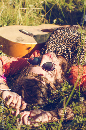 nature, summer vacation, vacation and people concept - happy smiling woman in sunglasses lies on the grass in a summer field. photo