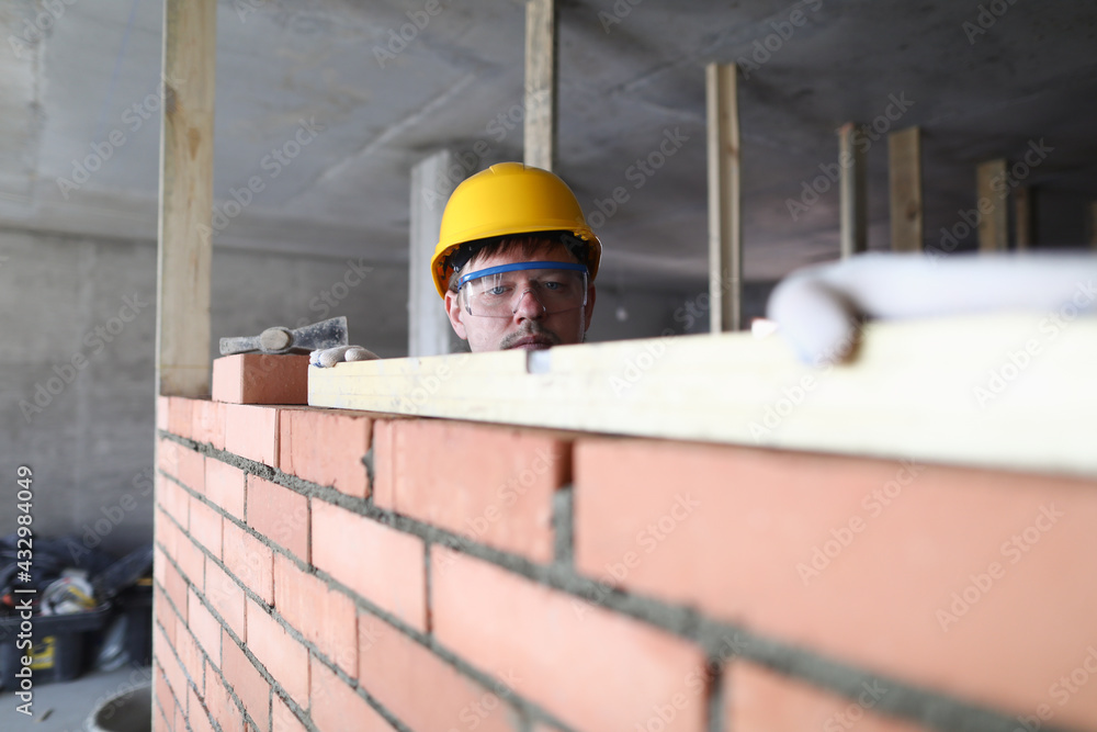 Portrait of builder laying bricks using special tools. Worker building brick walls Portrait of builder laying bricks using special tools. Worker building brick walls