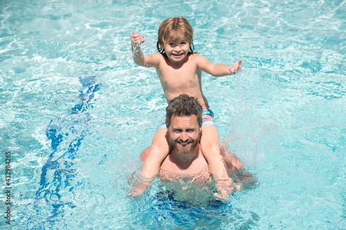 Father and son in pool. Family summer vacation. Pool party. Boy with dad playing in swimming pool. Active lifestyle.